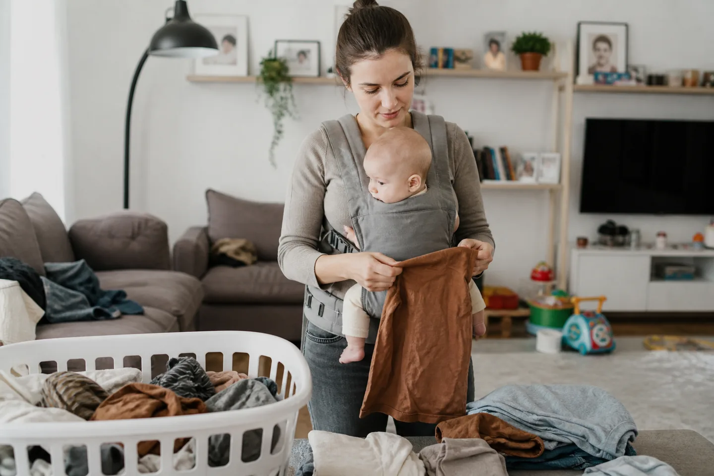 Caregiver adjusting an unbranded baby carrier in a calm home entry before a short walk